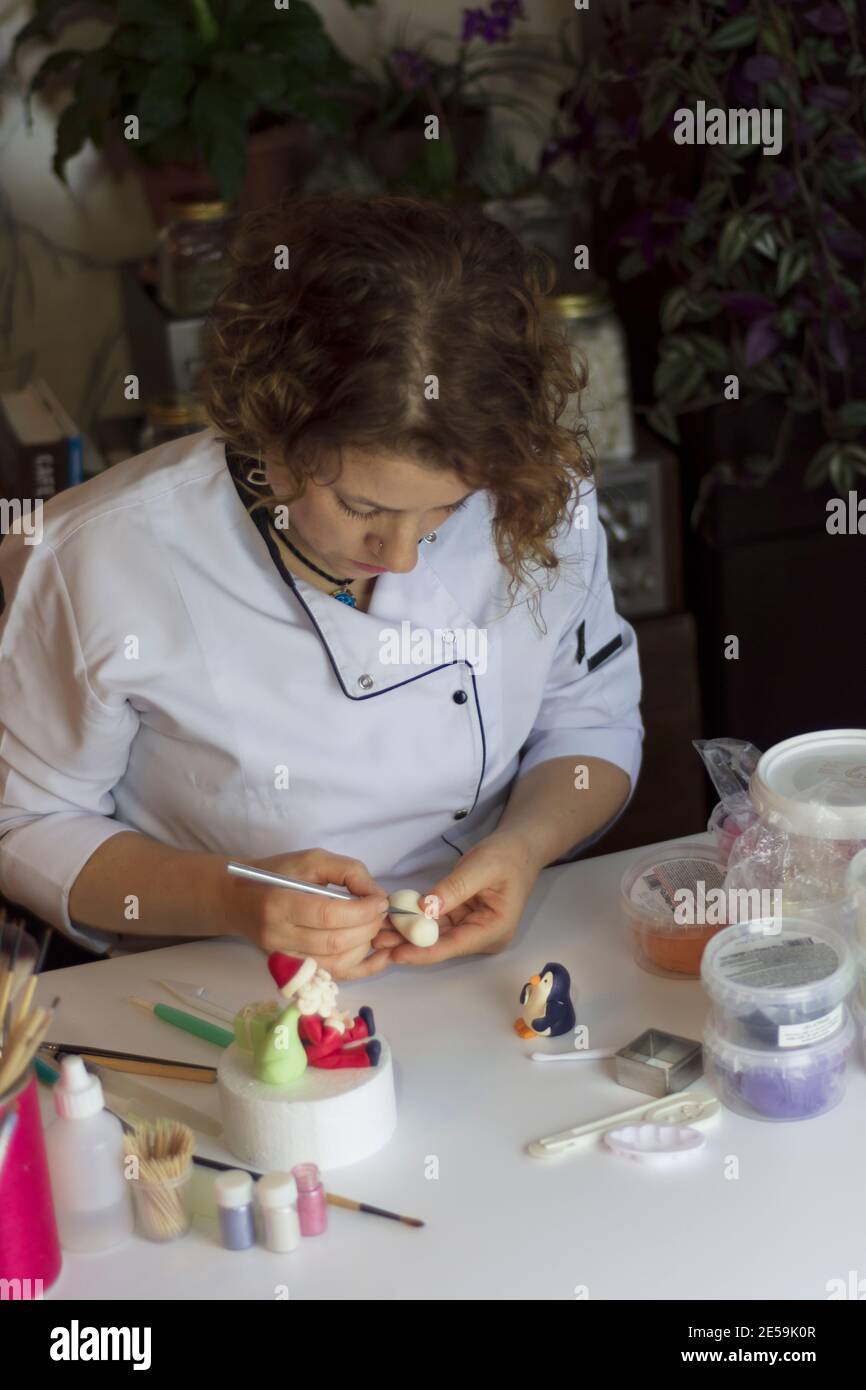 Cake decorating process. Baker uses tools to sculpt fondant patterns ...