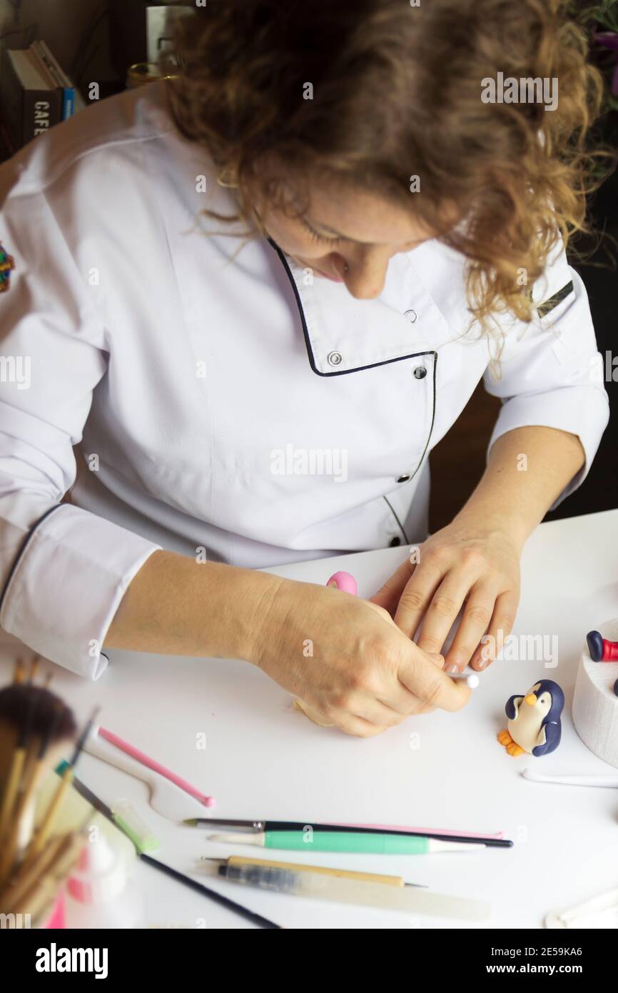 Cake decorating process. Baker uses tools to sculpt fondant patterns ...