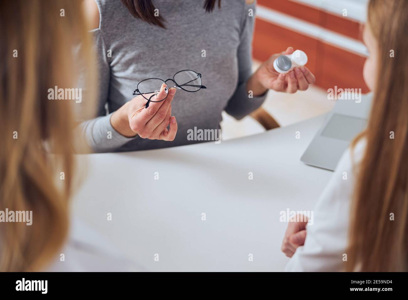Woman seller demonstrating modern lens and eye glass in optician clinic Stock Photo