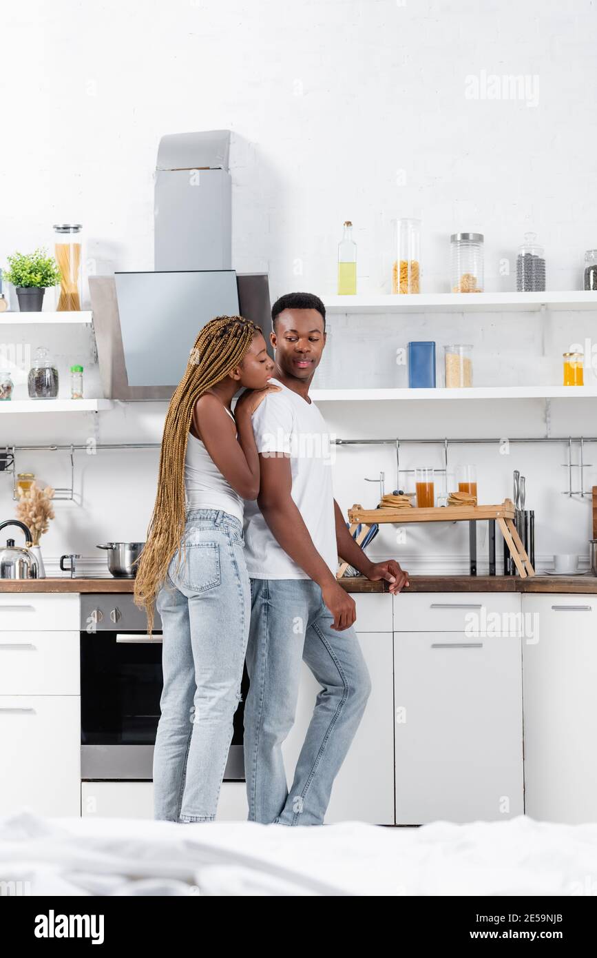 African american woman hugging boyfriend near breakfast on tray in ...