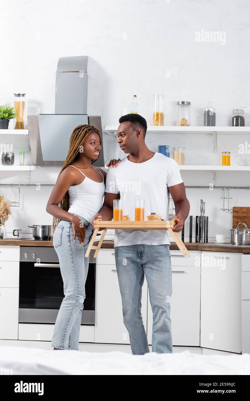 Smiling african american woman hugging boyfriend with orange juice and ...