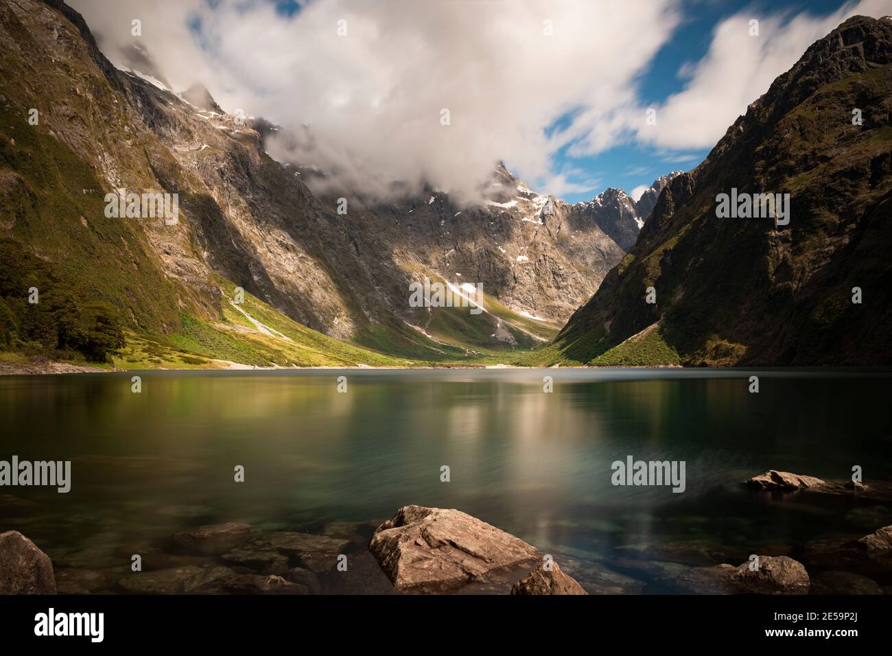 Lake Marian with low clouds cast shadows on the deep valley, Fiordland
