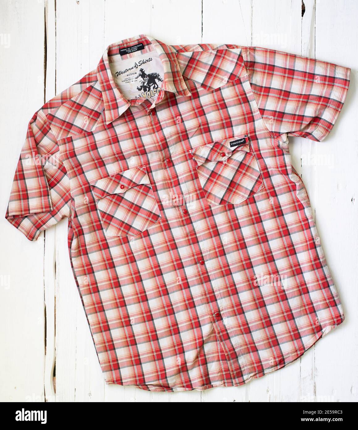 A red checked Volcom shirt on a white wooden background Stock Photo