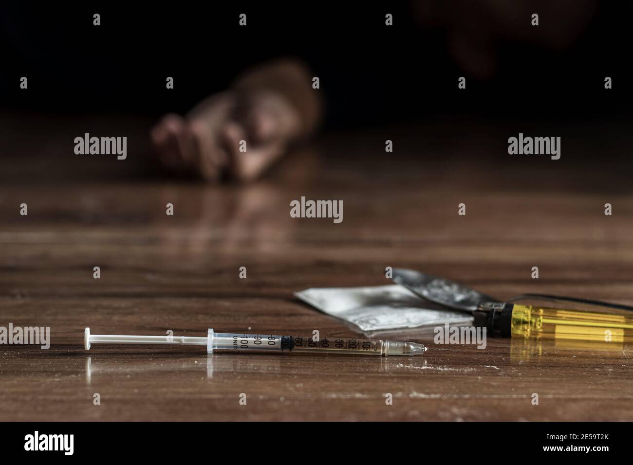 drug addict , junkie problem concept. close up of drug syringe and cooked heroin on the floor with drug addict hand reach out from black background Stock Photo