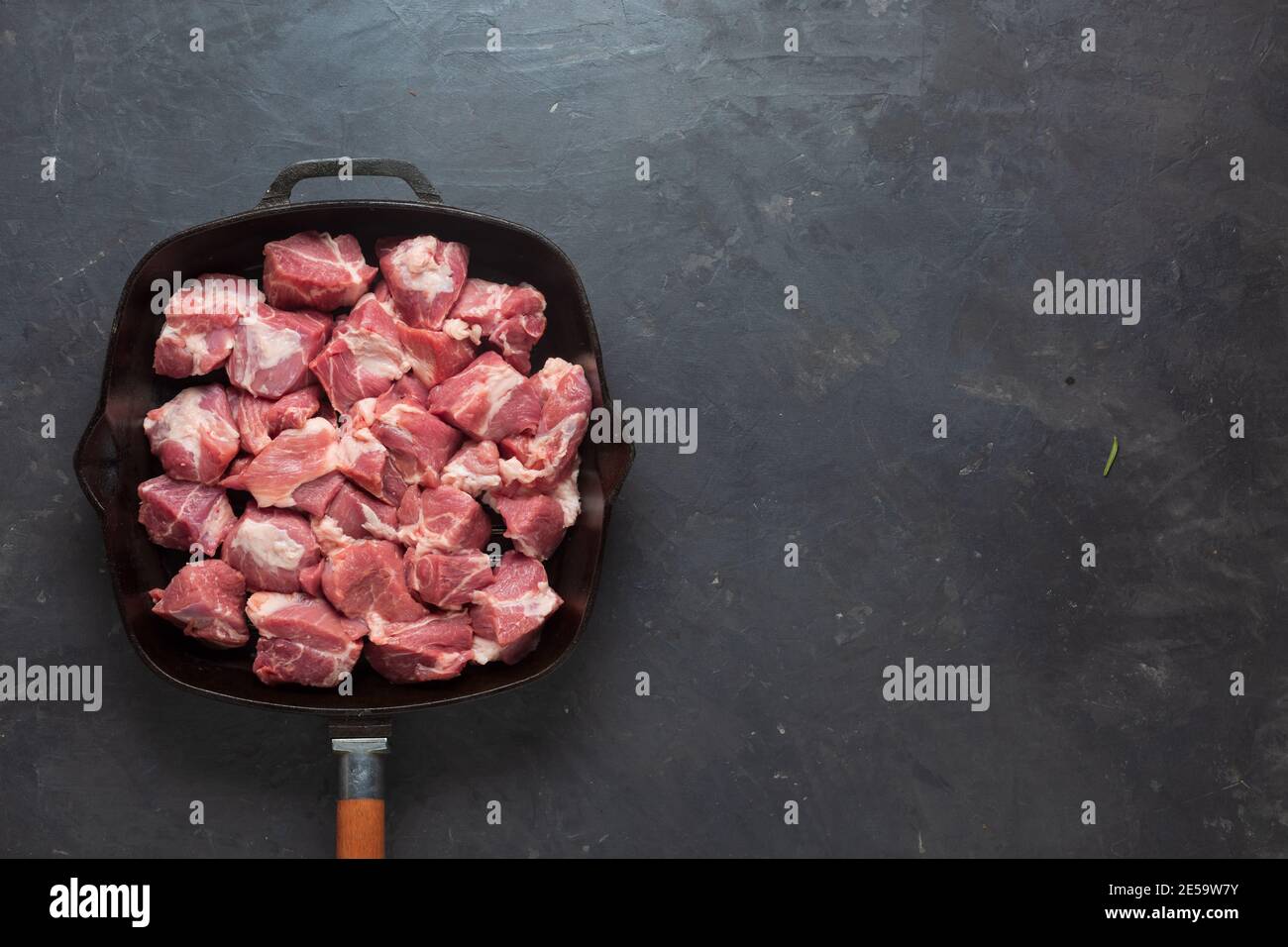Heap small pieces raw meat in frying pan, top view Stock Photo