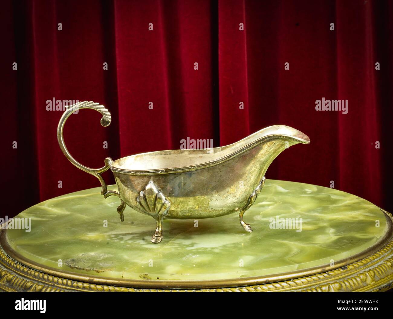Sauciere, saucer - Ornate metal gravy boat, vintage old fashioned dish on a red background Stock Photo