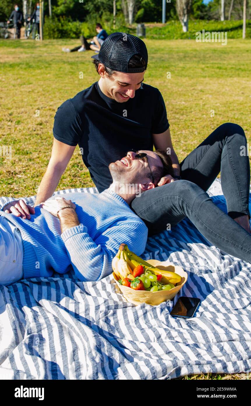 Vertical Shot of Young Adult Gay Couple Enjoying a Picnic at the Park in  Spring With Fruit Basket Stock Photo - Alamy