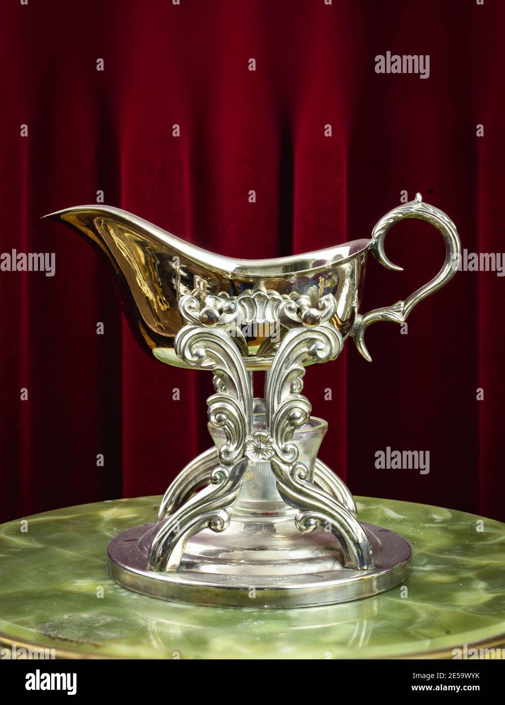 Sauciere, saucer - Ornate metal gravy boat, vintage old fashioned dish on a red background Stock Photo