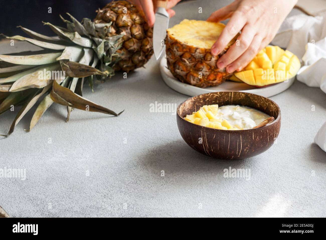 healthy breakfast consept, yogurt with fresh mango and pineapple in the coconut bowl Stock Photo