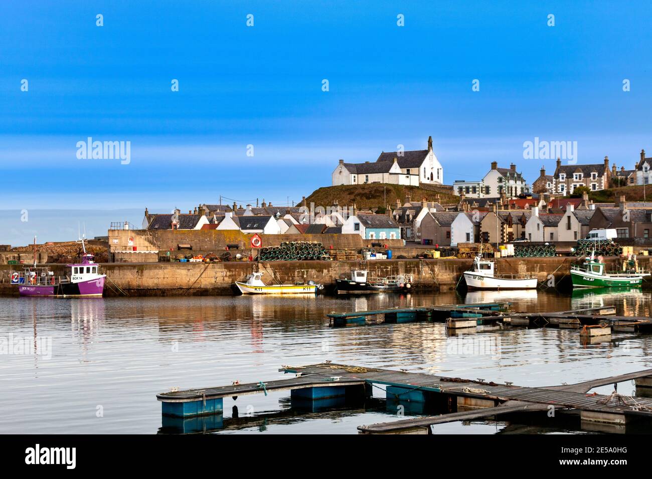 FINDOCHTY MORAY COAST SCOTLAND FISHING BOATS INSIDE THE HARBOUR WHITE CHURCH AND HOUSES ON THE HILL Stock Photo