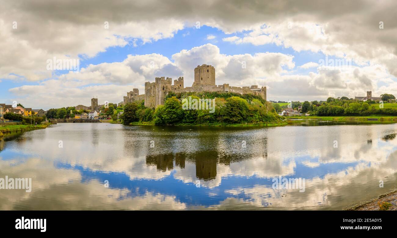 Panoramic view of Pembroke Castle (Castell Penfro) in Pembroke, county town of Pembrokeshire, south west Wales, UK reflected in water in the moat Stock Photo