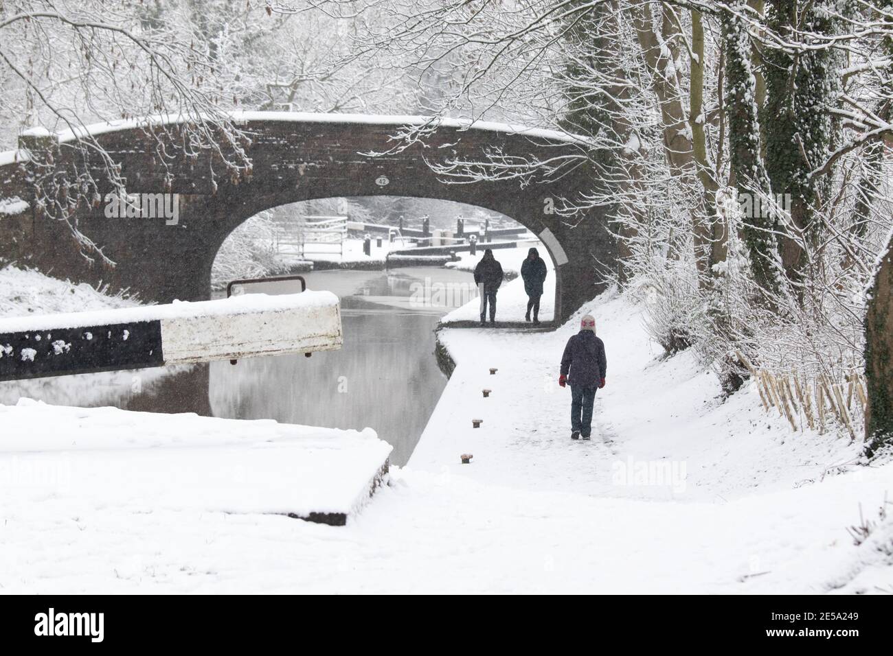 The snow covered scene along the Coventry canal near Atherstone, North Warwickshire. Pictured are walkers along the canal near the centre of Atherstone Town. Stock Photo