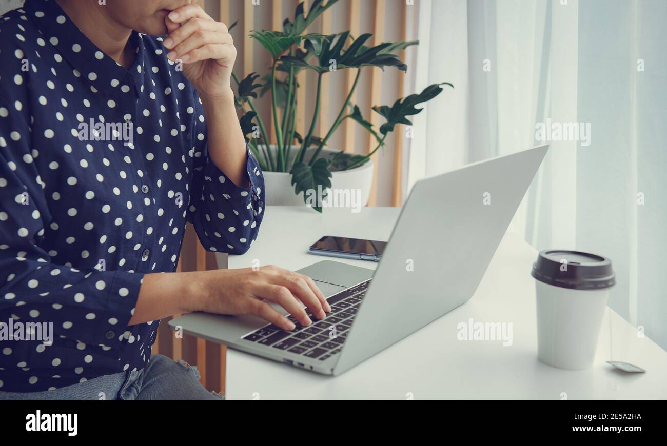Worried young woman using laptop and thinking about problem solution. Thinking about solution for the problem.Work at home advice to stop coronavirus Stock Photo