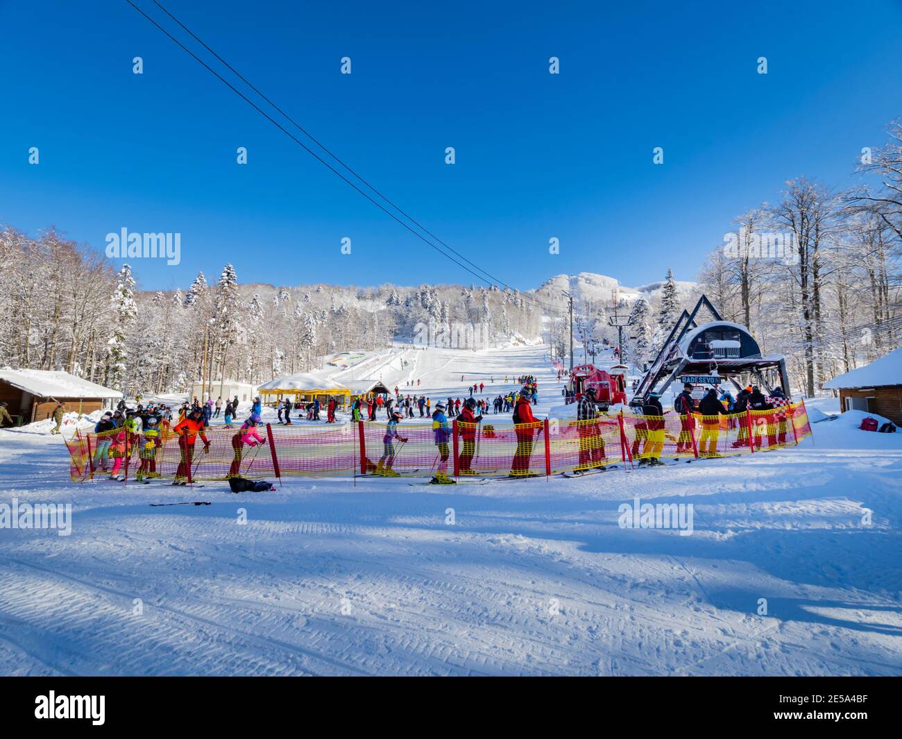 Sunshine on Platak Radesevo ski resort in Croatia Europe skiers queuing wait in row for lift Stock Photo