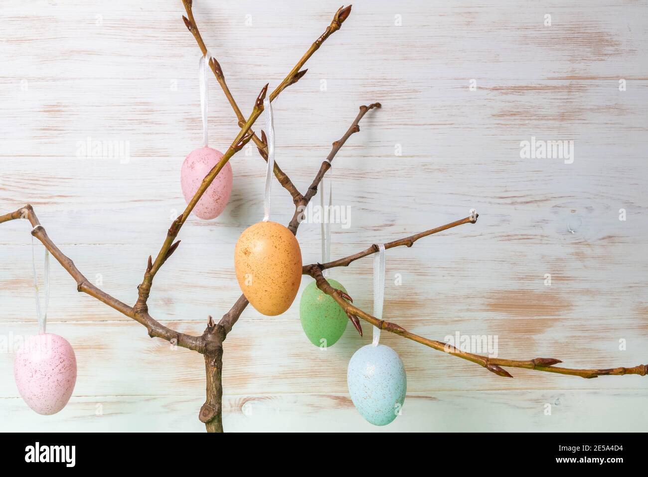 Easter decorative eggs hanging on branches in spring. Colorful Easter mood background. Easter time concept. Copy space. Stock Photo