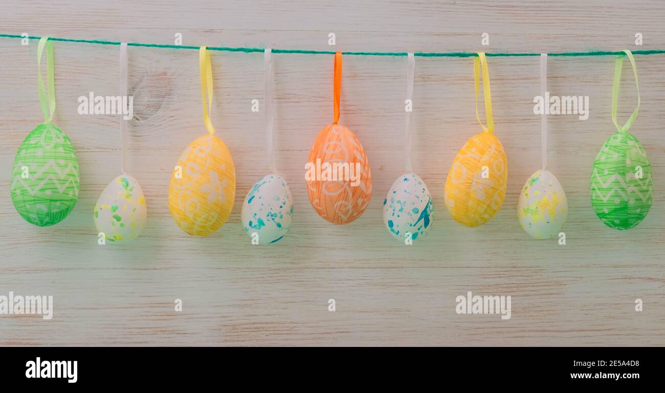 Easter eggs in row hanging on ribbons in springtime. Easter mood, gentle color background. Easter time decoration Stock Photo