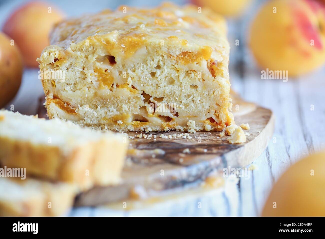 Delicious homemade peach sweet bread with frosting and fresh peaches. Selective focus with blurred foreground and background. Stock Photo