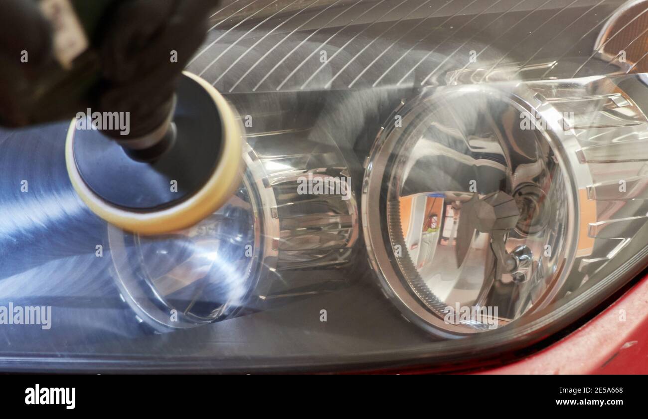 hand of a mechanic polishing the headlights of a car to make them shiny with a polishing machine Stock Photo