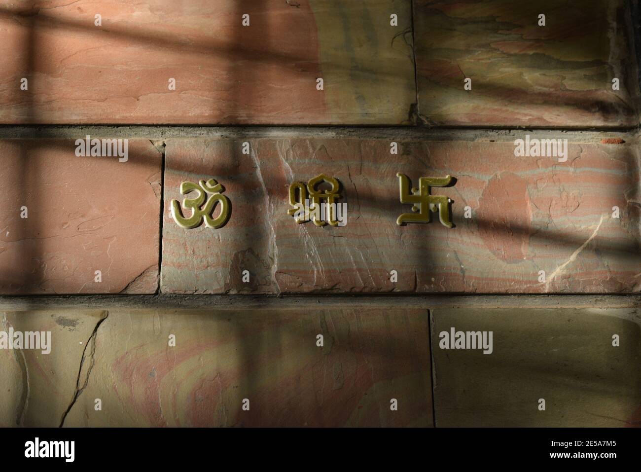 Om Shree Swastik stickers on a wall with sunlight shining on them Stock Photo