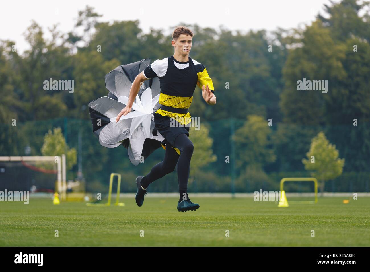 Youth Football Player Running with Parachute. Soccer Football Endurance Training. Speed or Sprint Testing. Professional Soccer Strength Test. Young Bo Stock Photo