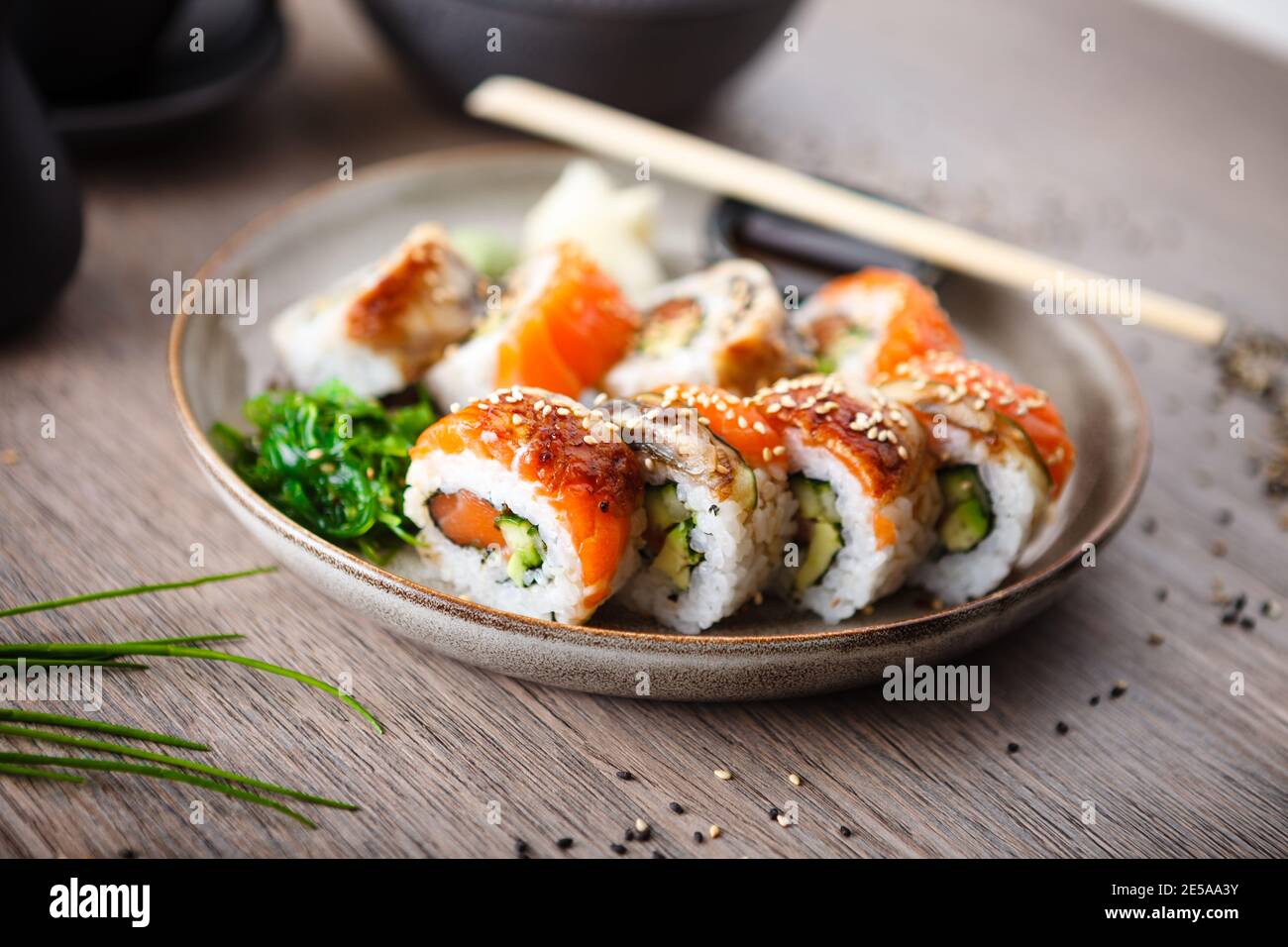Sushi maki rolls with salmon, eel, avocado, cucumber on a plate with chopsticks, soy sauce, wasabi and ginger. Japanese traditional fish food closeup Stock Photo
