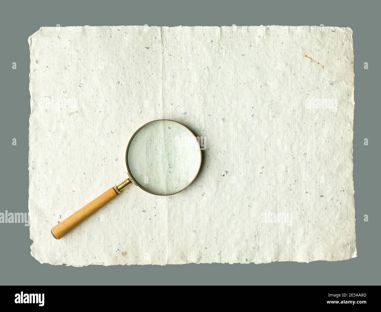 Recycled cream, grey vintage horizontal note paper texture. Vintage magnifier on top. Stock Photo