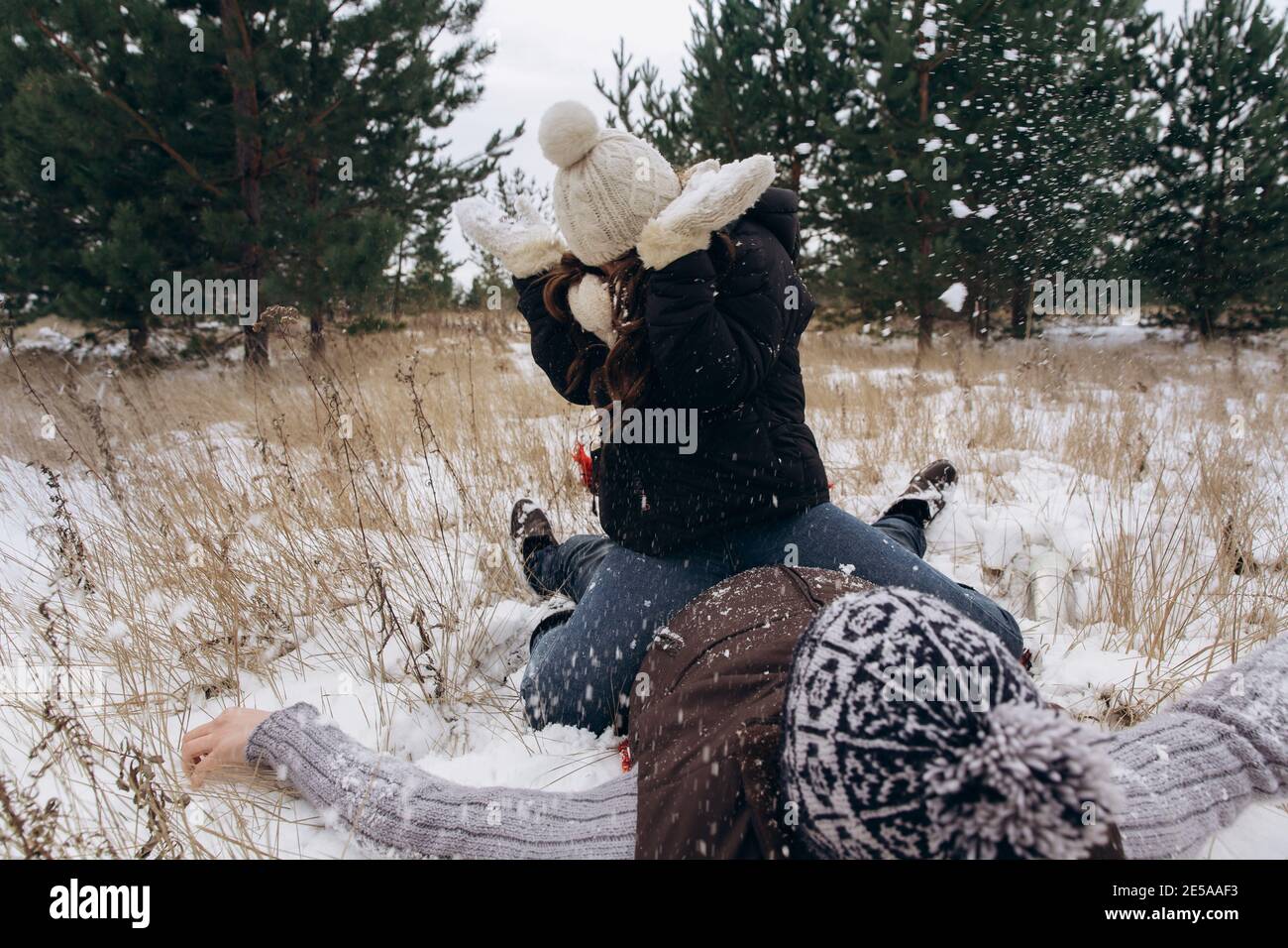The woman sits on the man. Couple playing snowballs in a winter snowy ...