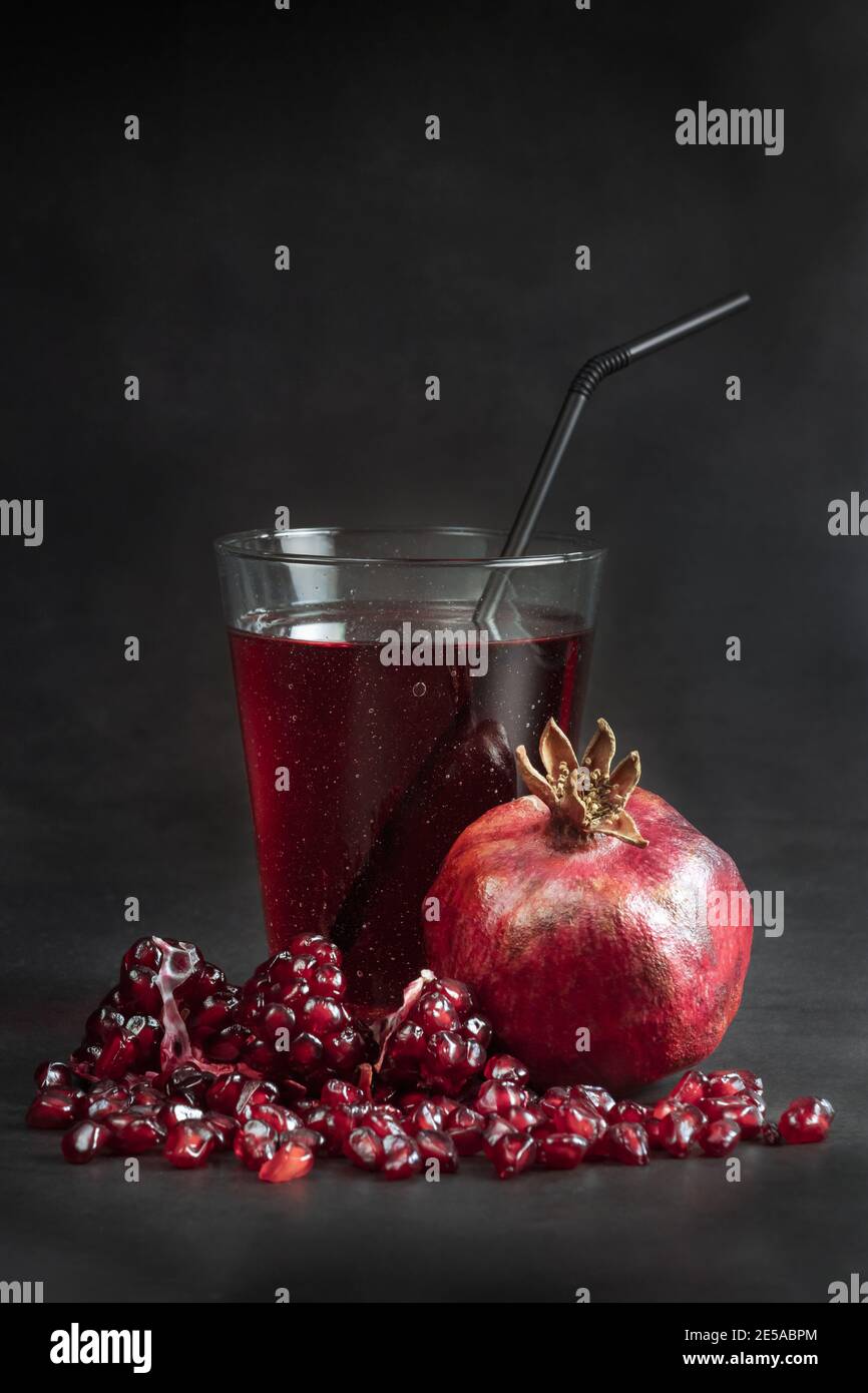 Pomegranate juice and fresh grenadine fruit on the table at black background. Stock Photo
