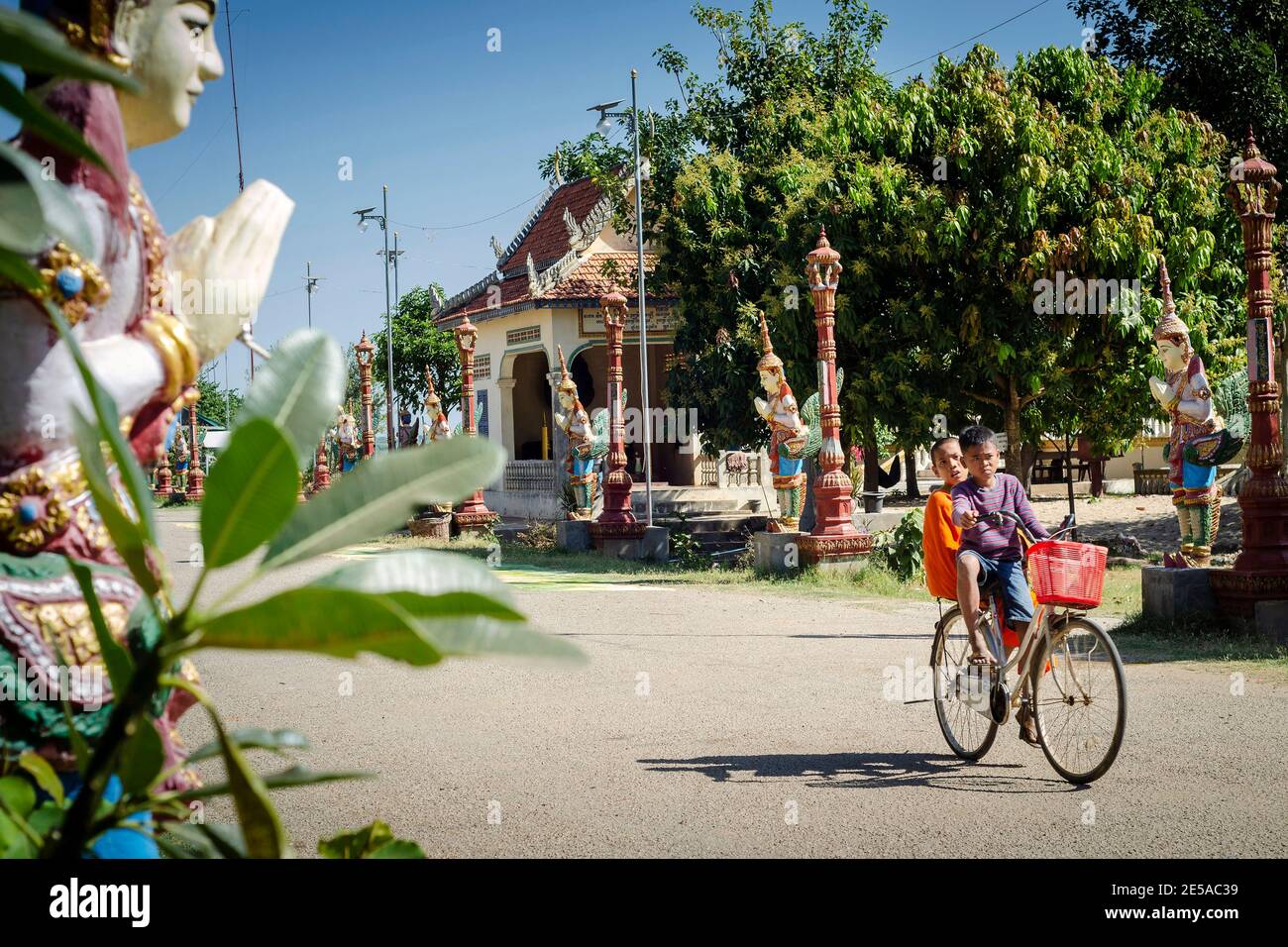 khmer children cycling at wat svay andet temple gardens in cambodia on sunny day Stock Photo