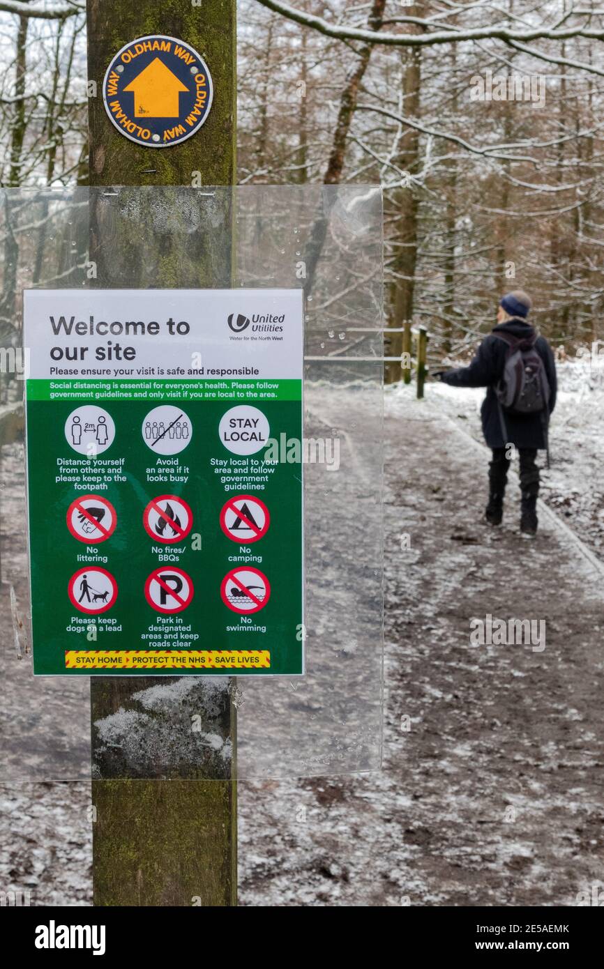 A visitor to Dove Stone Nature Reserve passes a Covid information poster in Binn Green car park. Stock Photo