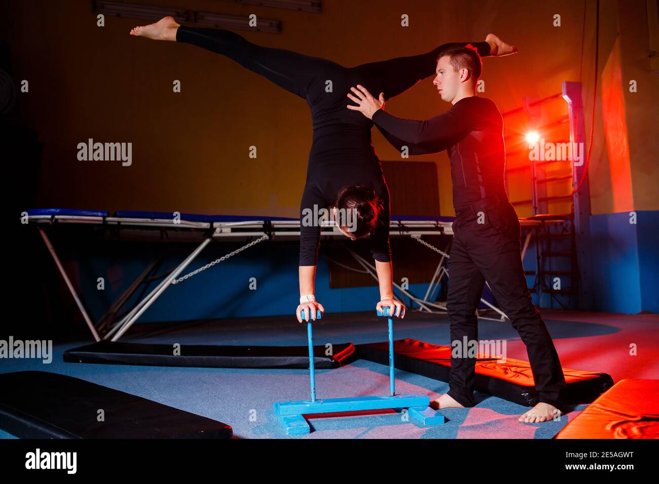 Young woman and man gymnasts do acrobatic exercises in the gym. Sports ...