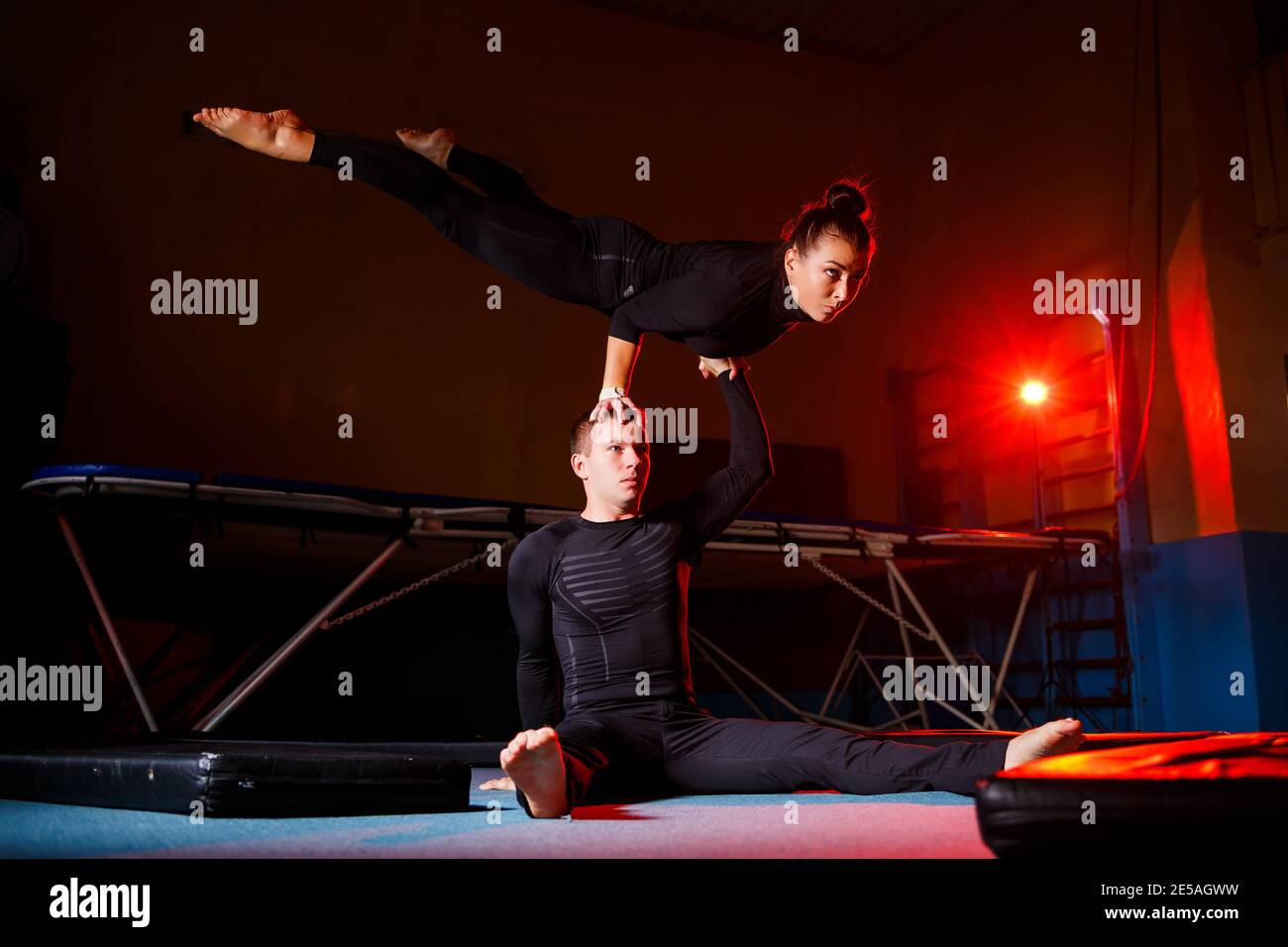 Young woman and man gymnasts do acrobatic exercises in the gym. Sports ...
