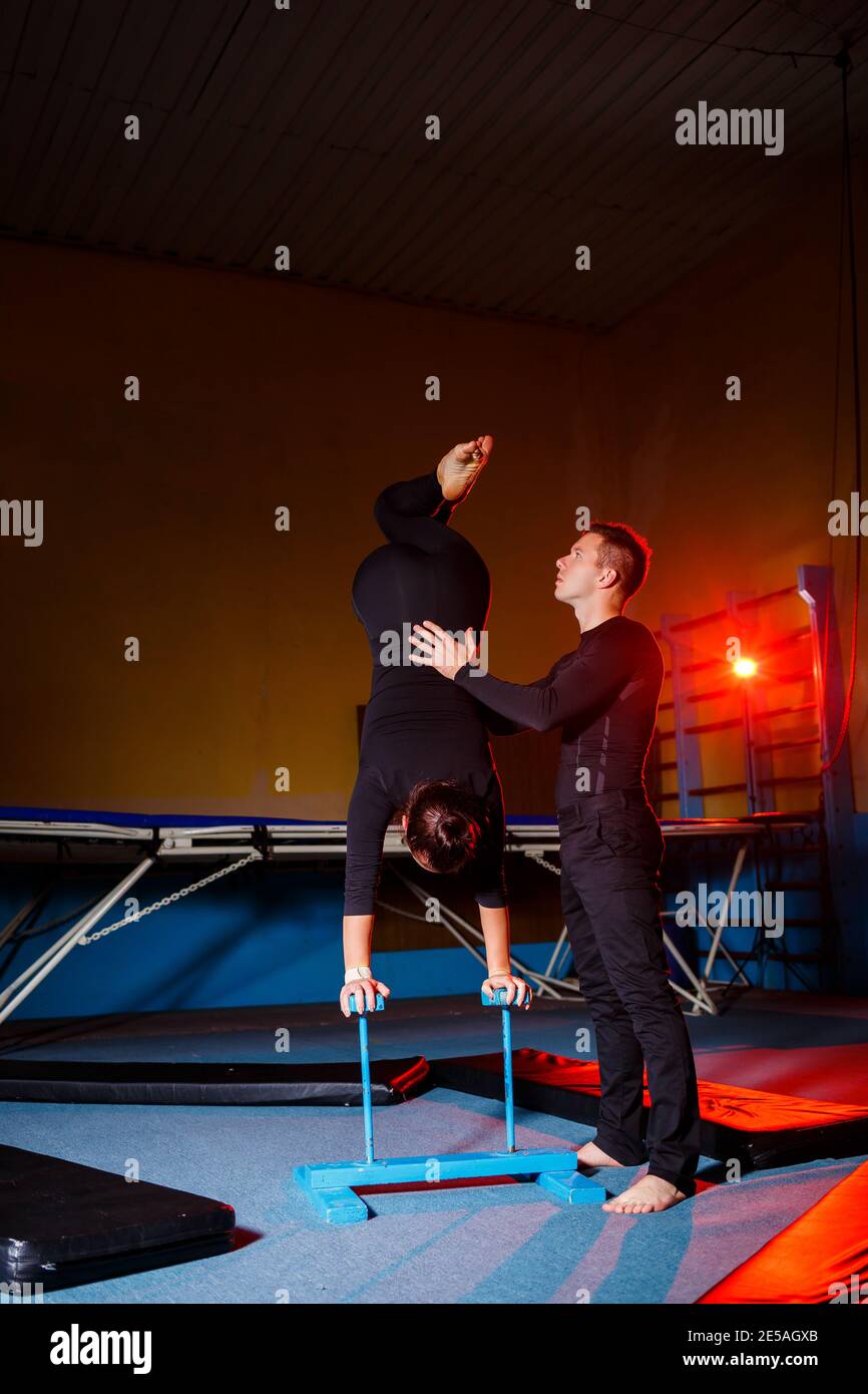 Young woman and man gymnasts do acrobatic exercises in the gym. Sports ...