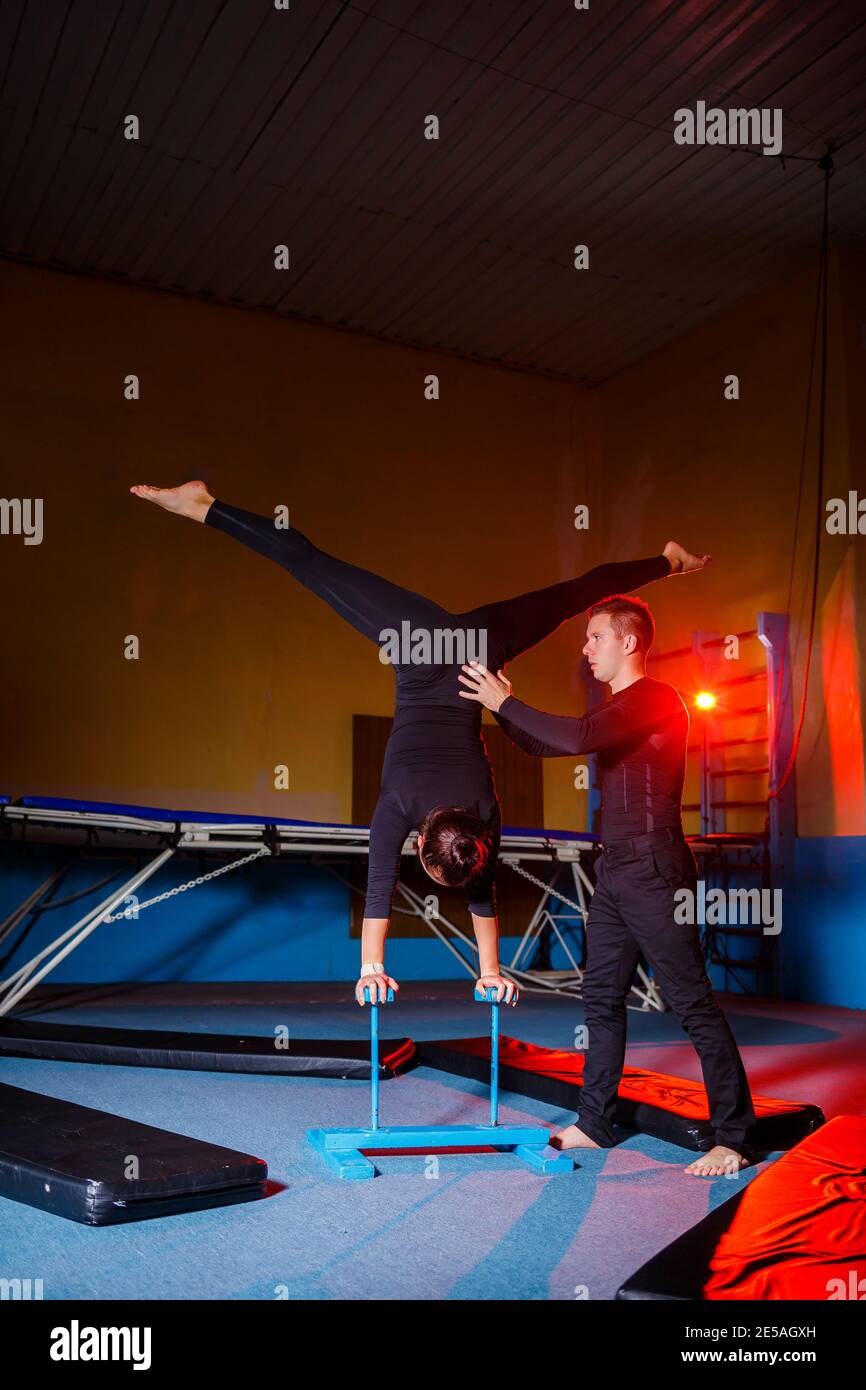 Young woman and man gymnasts do acrobatic exercises in the gym. Sports ...