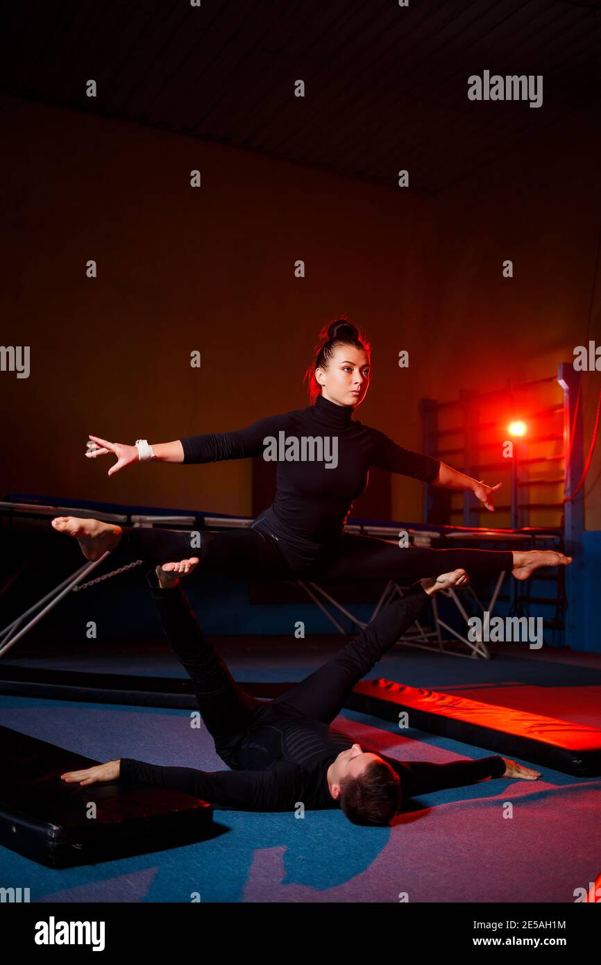Young woman and man gymnasts do acrobatic exercises in the gym. Sports ...
