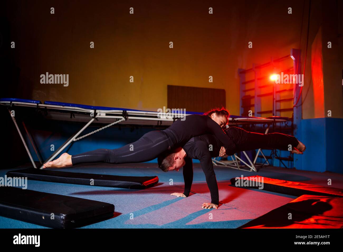 Young woman and man gymnasts do acrobatic exercises in the gym. Sports ...