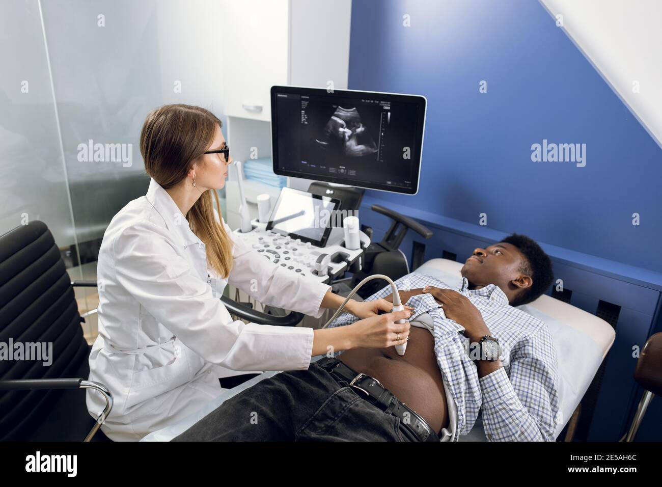 Young female doctor using ultrasound machine in modern clinic, makes
