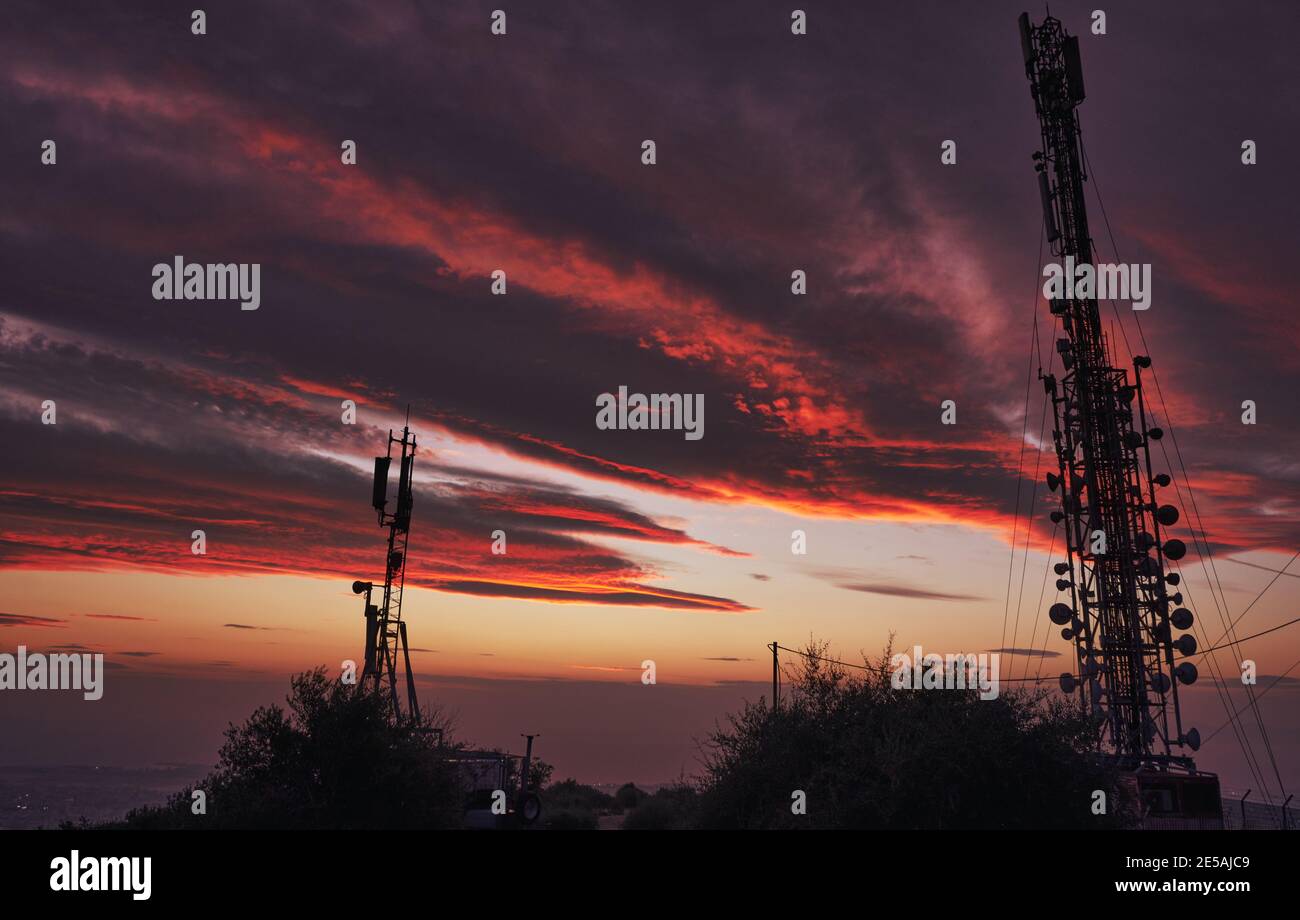 Extraordinary clouds on fire over the antenna after the sunset in Attiki, Greece Stock Photo