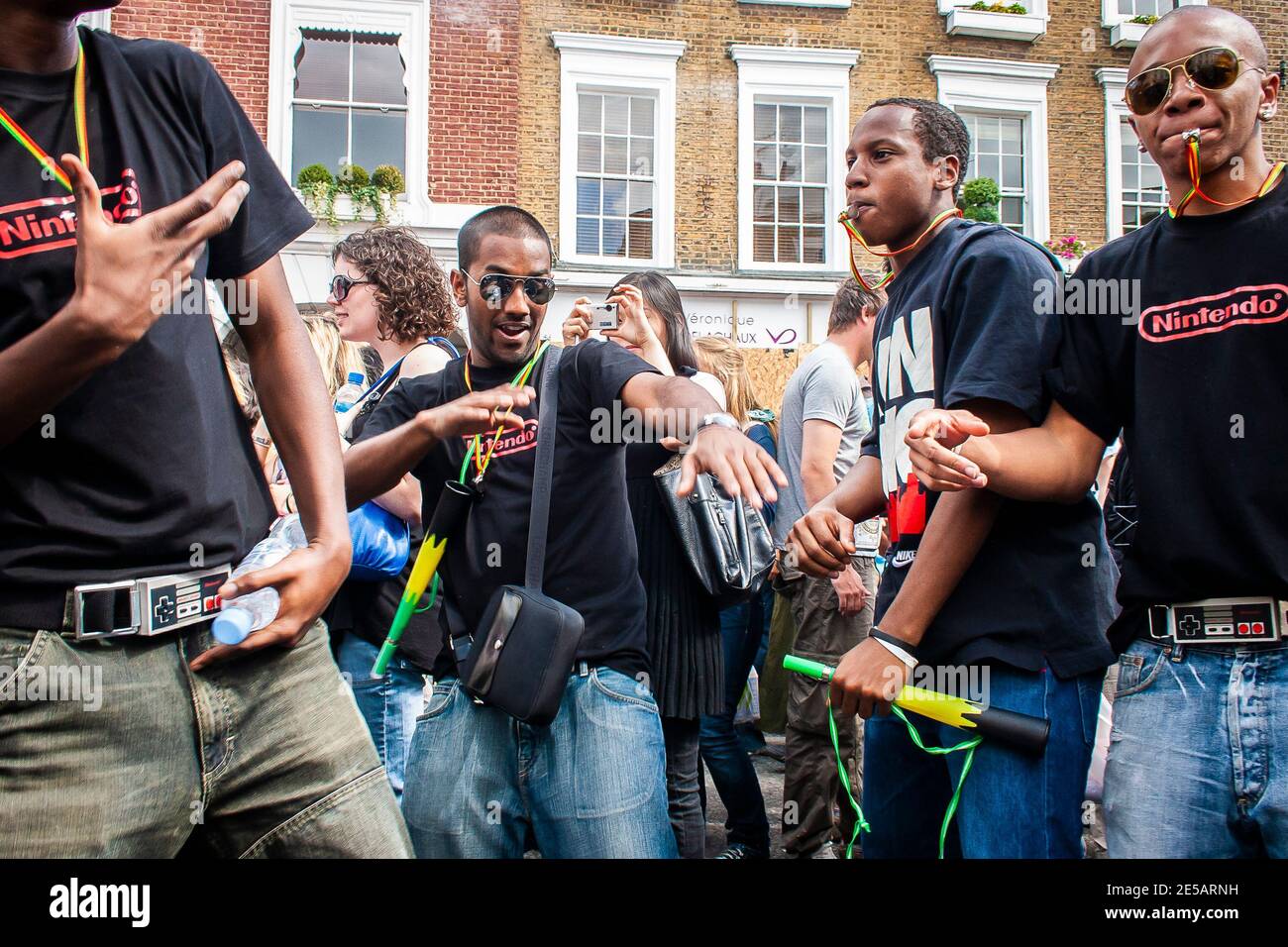 Group of friends blowing whistles having a great time at Notting Hill Carnival Stock Photo