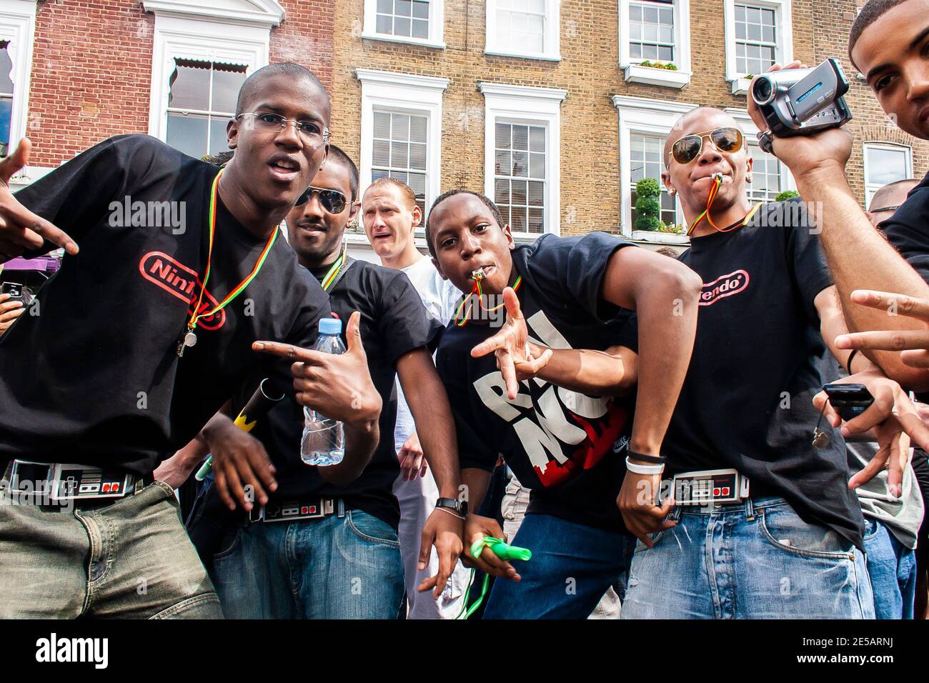 Group of friends blowing whistles having a great time at Notting Hill Carnival Stock Photo
