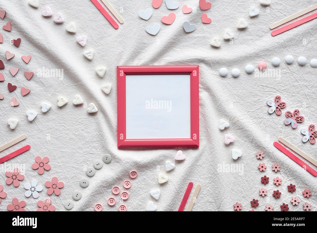 Abstract Springtime background. Pink picture frame with copy-space. Flat lay with hearts, candy, buttons, small decor arranged on textile background Stock Photo