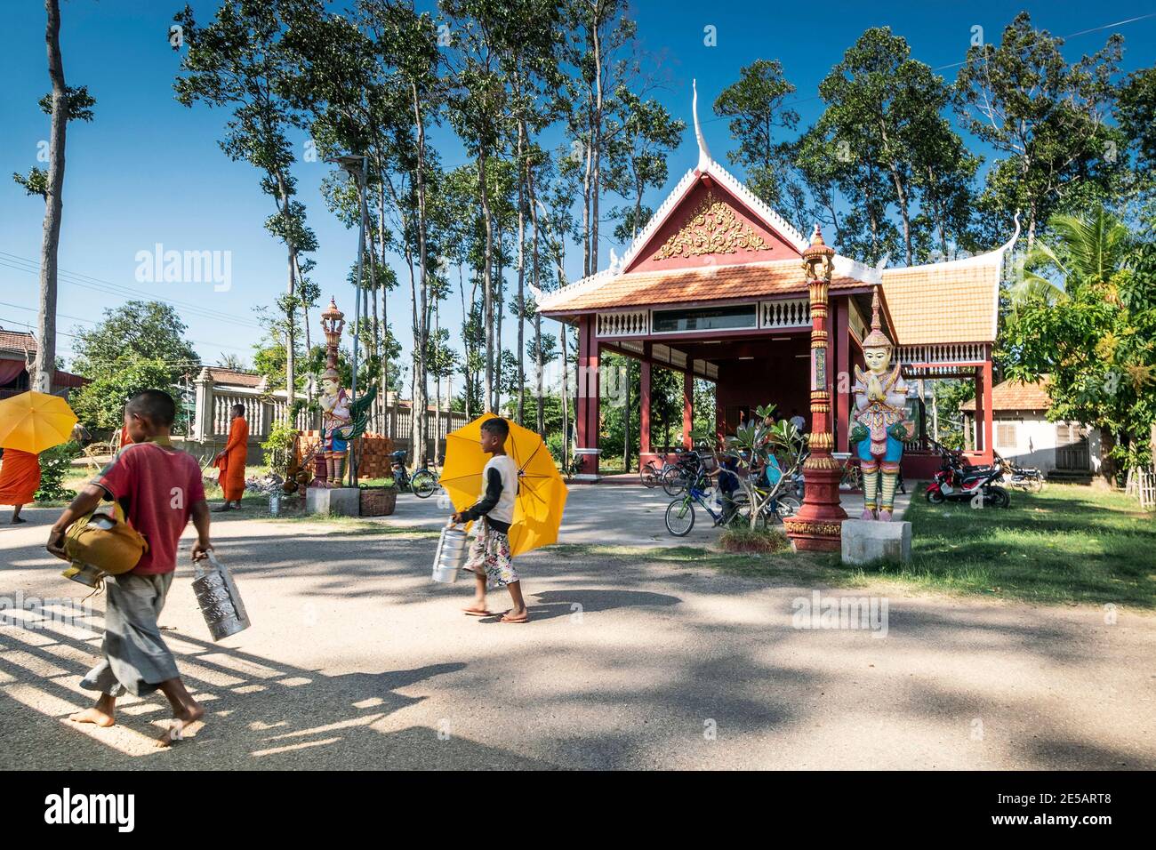 khmer children carrying lunch box tiffins at wat svay andet temple gardens in kandal province cambodia Stock Photo