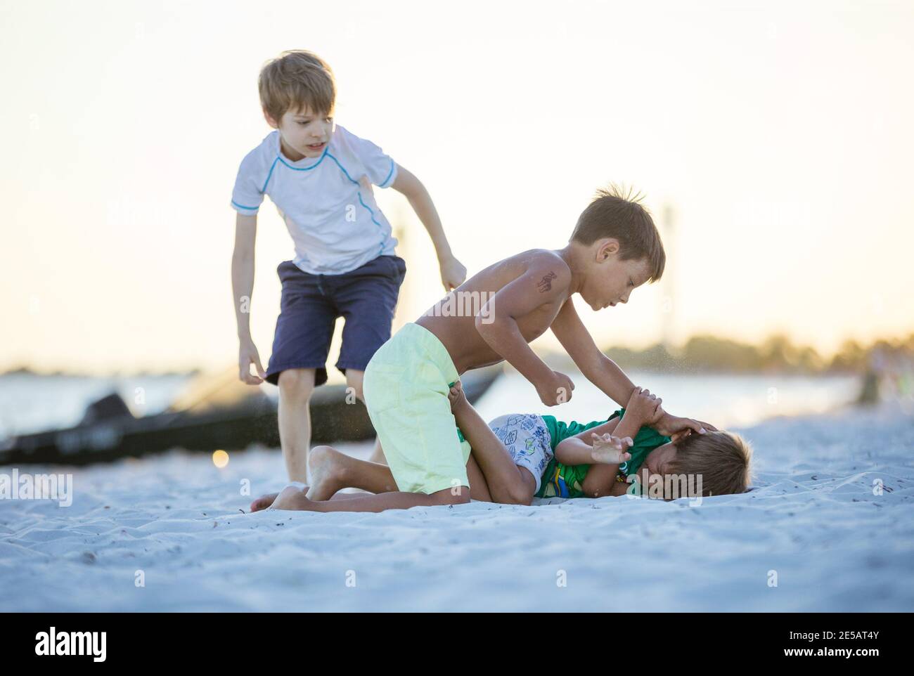Young boys fighting on beach, older boy going to hit younger one. Siblings rivalry. Stock Photo