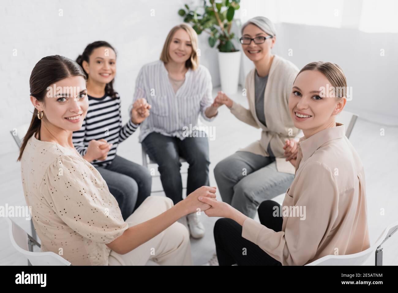 Happy Multicultural Women Holding Hands And Looking At Camera Stock