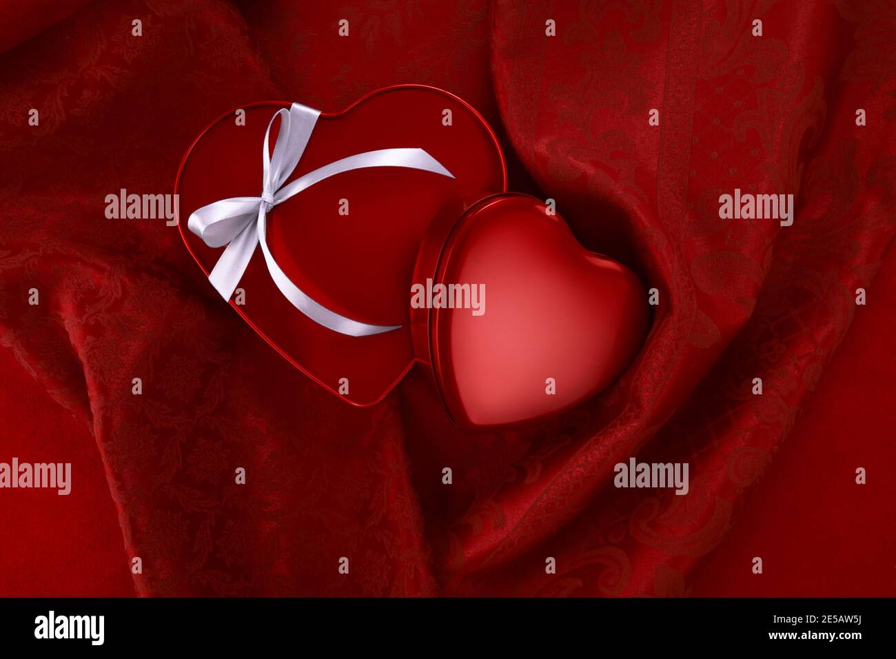 Valentine day, red heart shaped shiny metal packaging with ribbon bow ...