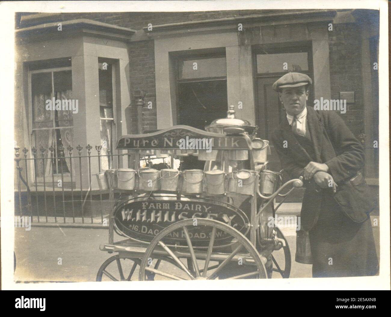 Snapshot of local delivery milkman with milk cans and cart circa 1925 in London Stock Photo