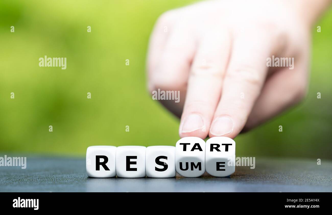 Hand turns dice and changes the word resume to restart. Stock Photo