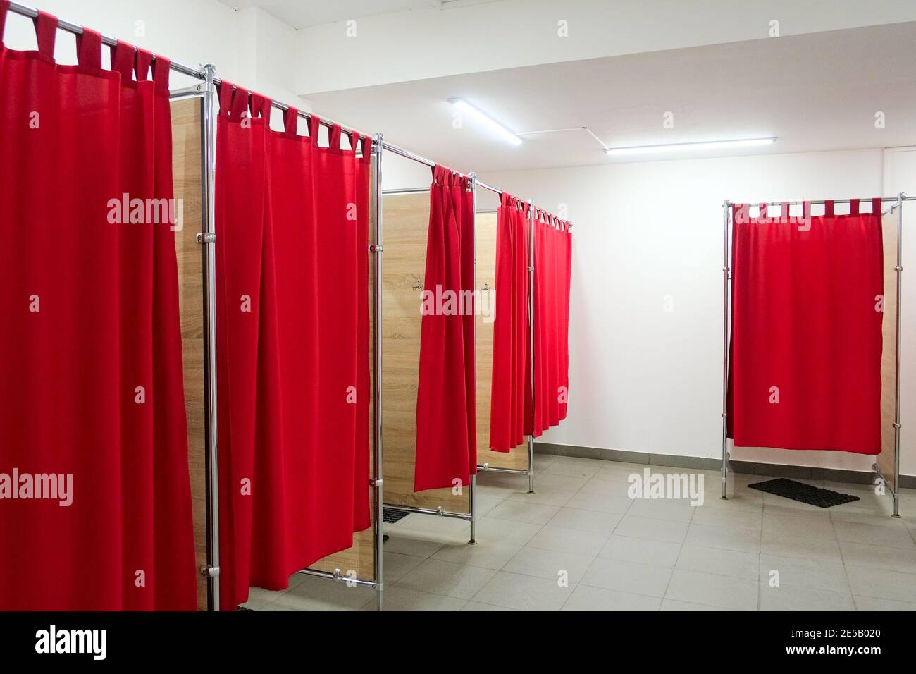 Empty fitting rooms with red curtains and white walls. Dressing rooms in clothing store with no people Stock Photo