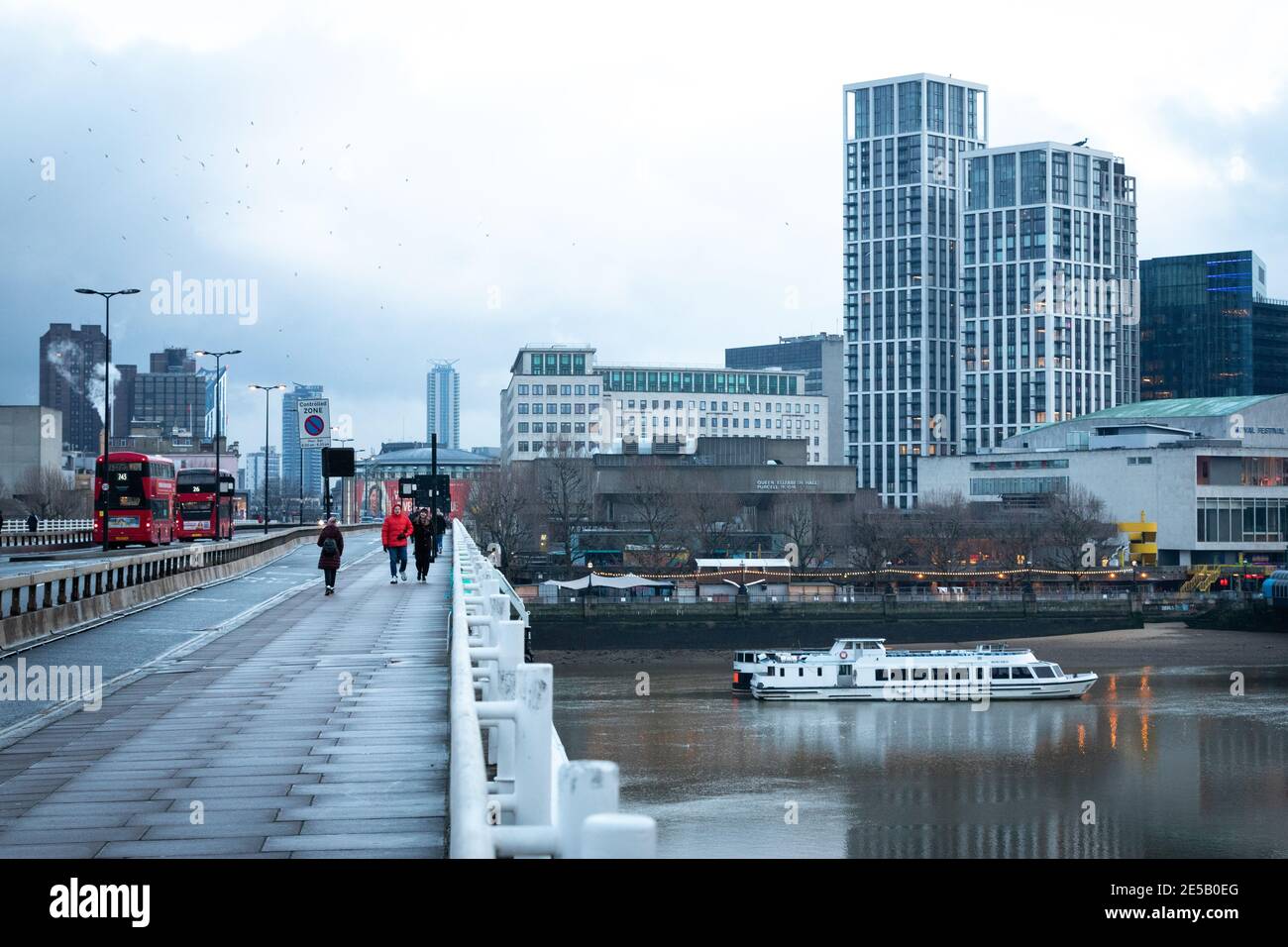 People walk along Waterloo bridge on a cold winter day. Stock Photo