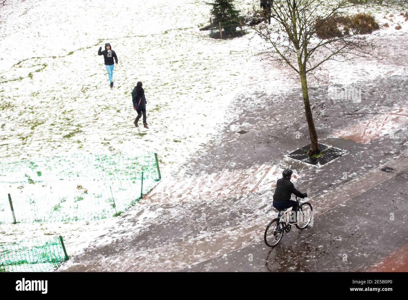 A man cycles through a park in Haggerston after some snowfall. Stock Photo